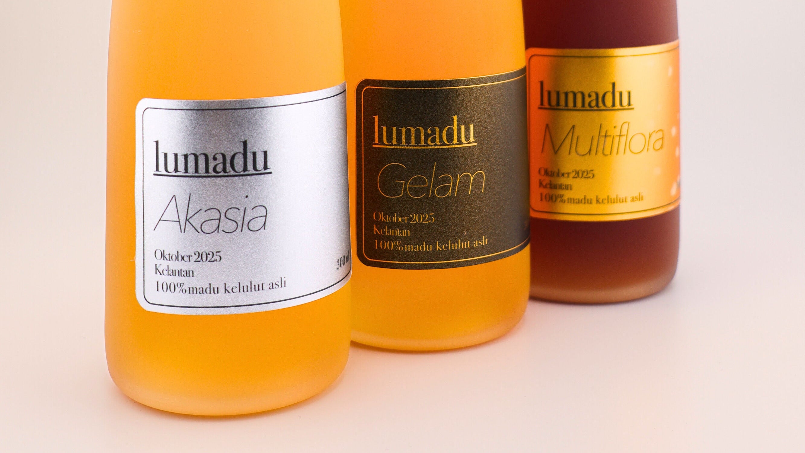 Three bottles of lumadu madu kelulut on a beige background